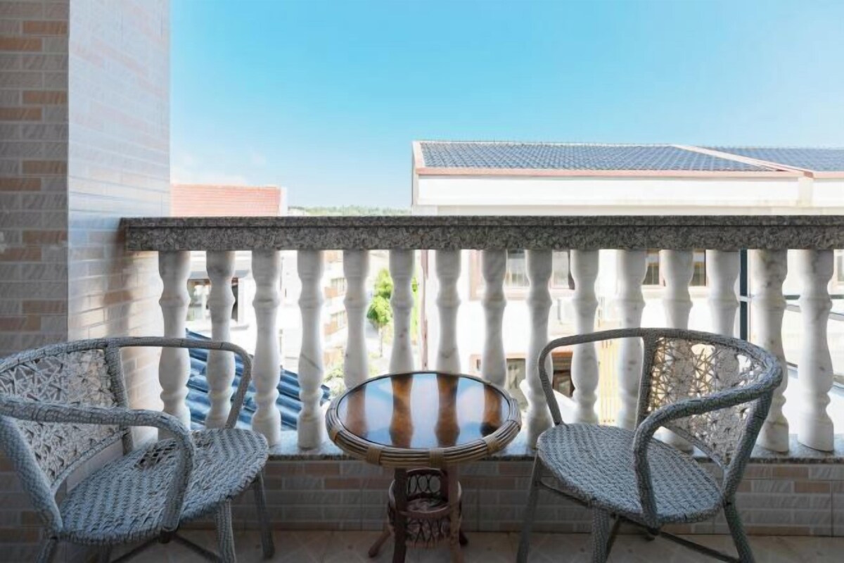 A balcony with two wicker chairs and a small round table.