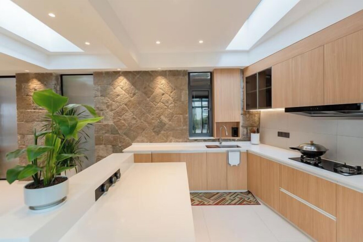 A modern kitchen with a stone accent wall, wooden cabinets, and a central island.