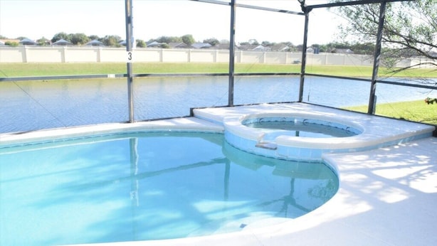 Een zwembad met een jacuzzi, omringd door een overdekt terras met een hek.