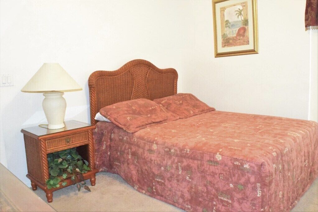 Ein Schlafzimmer mit Bett, Nachttisch mit Lampe und einer kleinen Pflanze.