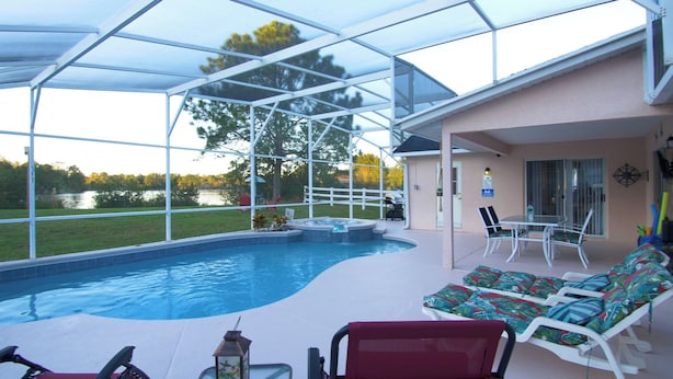 A covered outdoor swimming pool with lounge chairs and a hot tub. - Hummingbird Haven (Davenport)