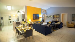 A modern living room with a dining area, featuring a sofa set, a coffee table, and a dining table with chairs. - Hummingbird Haven (Davenport)