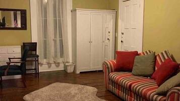 A living room with a sofa, a patterned armchair, a white cabinet, and a shaggy rug.