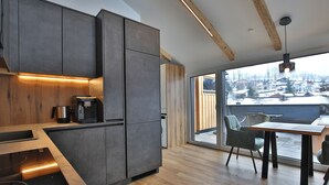 Una cocina moderna con armarios oscuros, encimera de madera y estufa integrada.