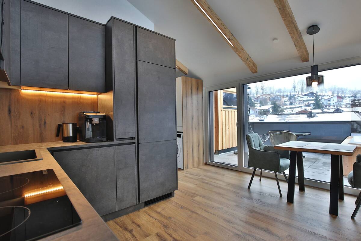 A modern kitchen with dark cabinets, a wooden countertop, and a built-in stove.