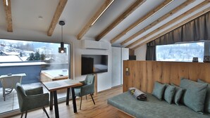 Una sala de estar moderna con techo de madera, un sofá con cojines, un televisor y un comedor con sillas y una mesa.