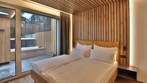 Un dormitorio moderno con una cama grande, paneles de madera y un ventanal corredero que da a un espacio exterior.