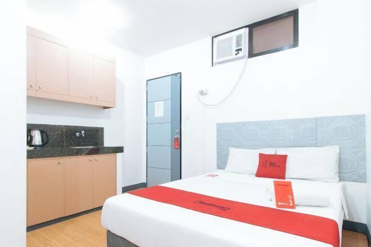 Ein Hotelzimmer mit einem Bett, einer Küchenzeile, einer Tür und einer Wand-Klimaanlage.