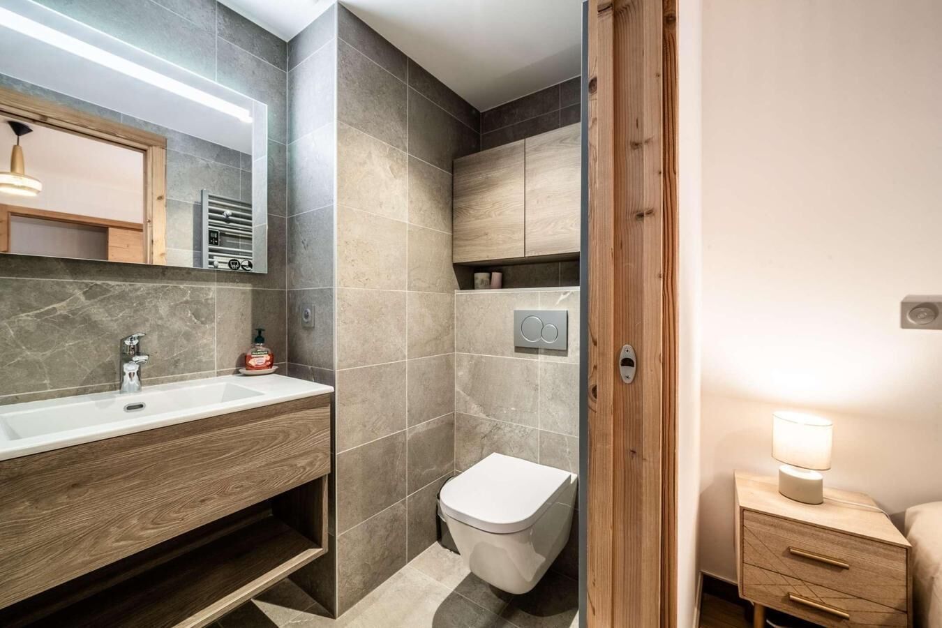 A modern bathroom with a wooden vanity, a toilet, and a shower area.