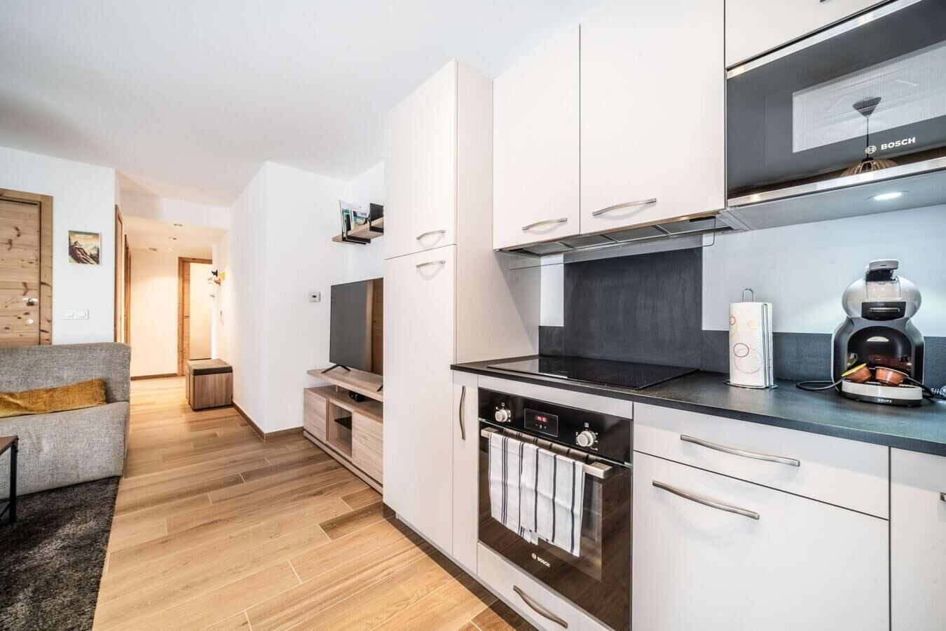 A modern kitchen with white cabinets, a Bosch oven, and a coffee machine.