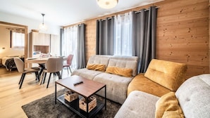 A modern living room with a sofa, a coffee table, and a dining area with chairs and a table.
