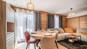 A modern living room with a dining area, wooden walls, and a cozy sofa.