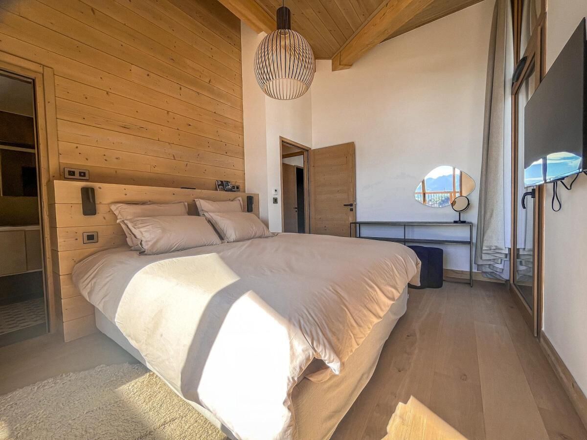 Un dormitorio con una cama grande, paredes de madera, un escritorio y un espejo.