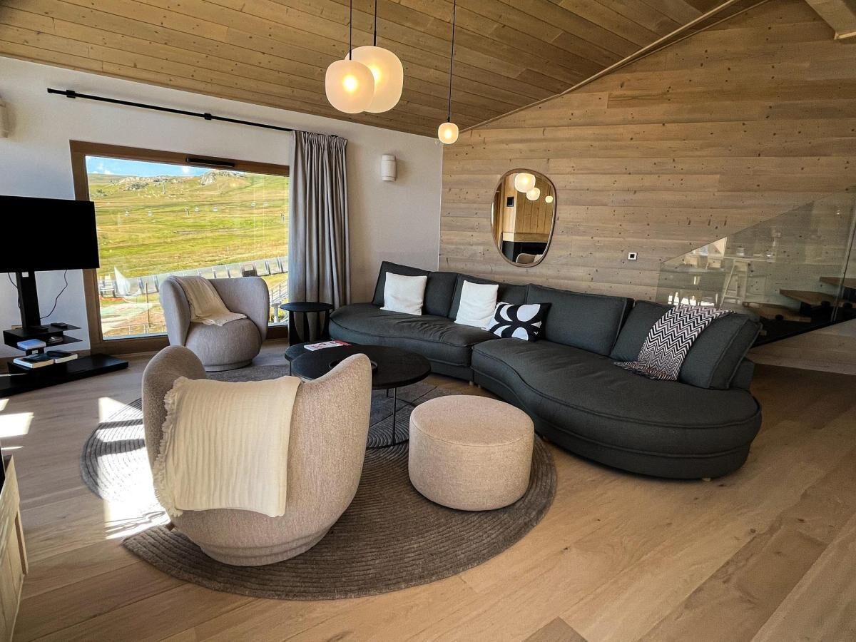 A modern living room with a sectional sofa, a round ottoman, and a unique chair.