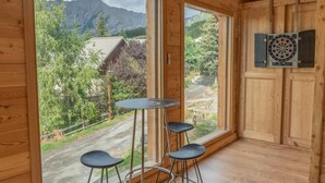 A wooden room with a large window, a dartboard, and a small table with stools. - Chalet, 350m from ski slopes, view valley, balcony, tv, ski locker, 205m², Les Orres (Les Orres)