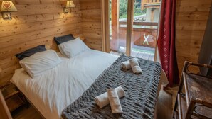 A wooden cabin room with a bed, two pillows, a blanket, and two towels. - Chalet, 350m from ski slopes, view valley, balcony, tv, ski locker, 205m², Les Orres (Les Orres)