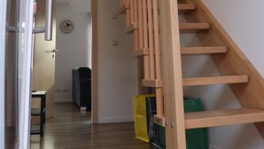 A wooden staircase with a handrail, leading to a landing with a door and a clock. - Naturferienhof Märkisch Luch - Trapphenne (Märkisch Luch)