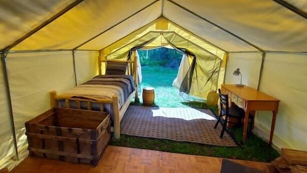 A tent with a bed, a wooden crate, a table, and a bench. - Trapper Wall Tent, Trapper Wall Tent by the Stream (Story)