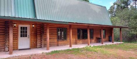 A log cabin with a metal roof, a porch, and a door.