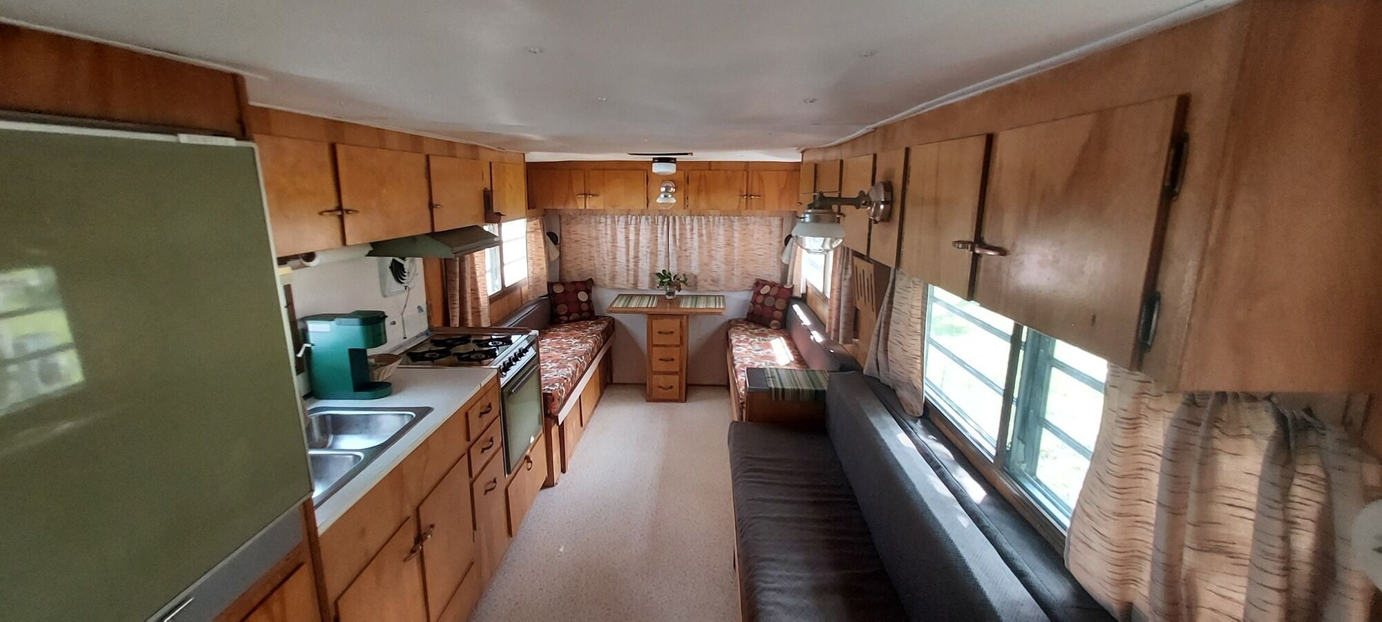 Cozinha compacta de motorhome com armários de madeira, fogão e pia.