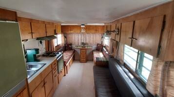 Een kleine camperkeuken met houten kastjes, een fornuis en een spoelbak.