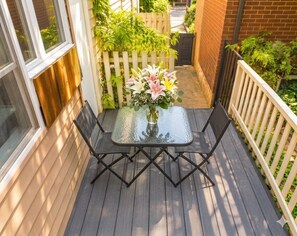 Une terrasse avec une table et des chaises, entourée d’une clôture en bois et de verdure.