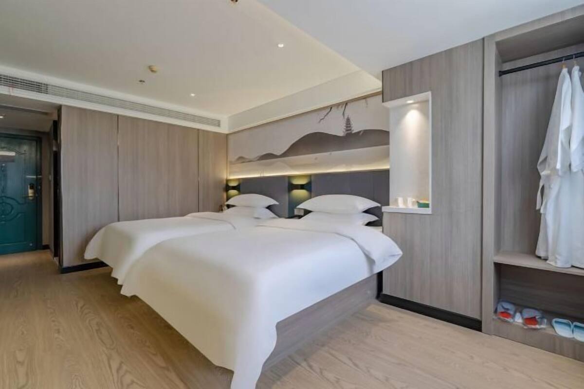 Une chambre d’hôtel moderne avec un grand lit, une armoire intégrée et une étagère fixée au mur.