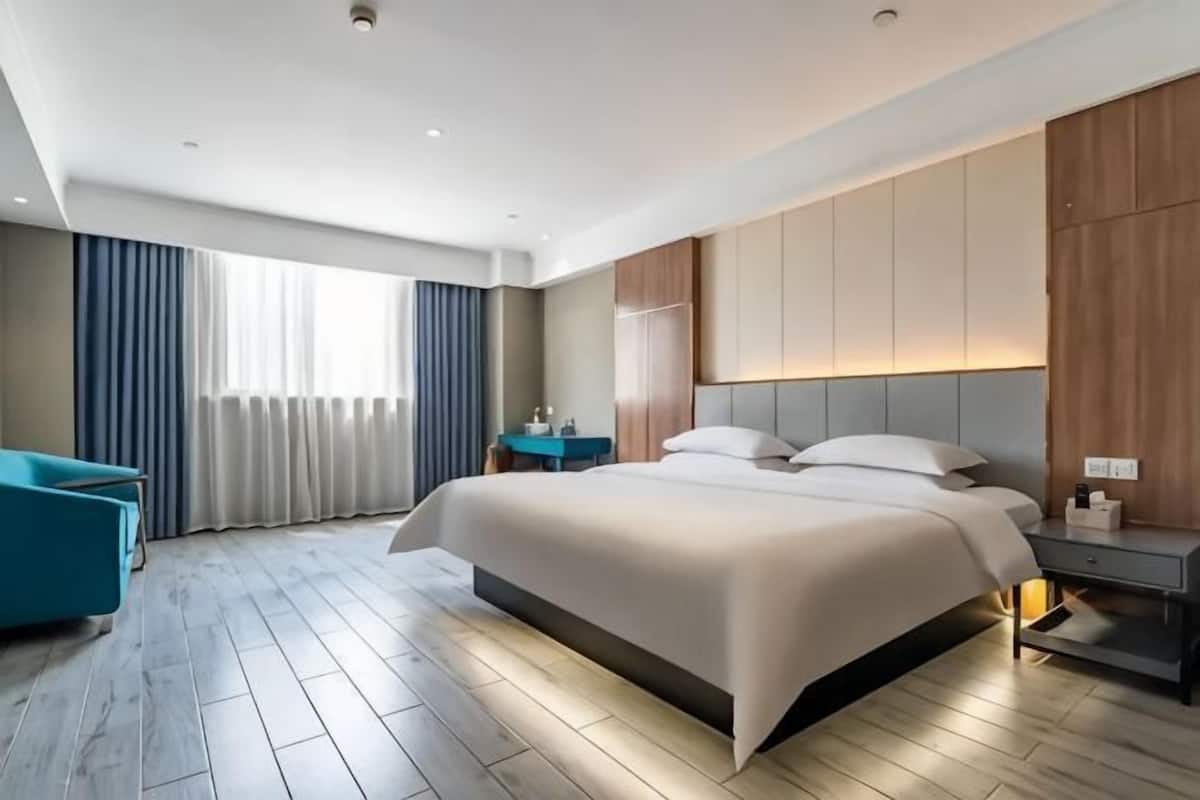 Une chambre d’hôtel moderne équipée d’un grand lit, d’une table de chevet, d’un bureau et d’un canapé.