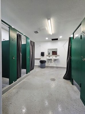 Ein sauberes, modernes Badezimmer mit grünen Kabinen, einem Waschbecken und einem Mülleimer.