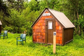A small wooden cabin with a sign reading 'Saint Neighbors' and the number 28 on a post.