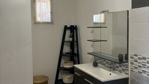A bathroom with a white sink, dark cabinets, a mirror, and a ladder against the wall. - Bright Apartment Near the Beach and Old Port (Marseille)