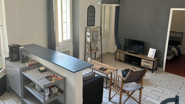 A compact living space with a kitchenette, a dining area, a TV, and a bed. - Bright Apartment Near the Beach and Old Port (Marseille)