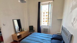 A bedroom with a bed, a dresser, a mirror, and a window with curtains. - Bright Apartment Near the Beach and Old Port (Marseille)