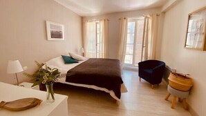 Ein Schlafzimmer mit Bett, Nachttisch, Lampe, Stuhl und einem kleinen Hocker.
