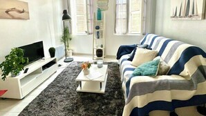 Ein Wohnzimmer mit einer Couch, einem Couchtisch, einem Fernseher und einer Pflanze.