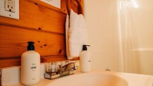 A bathroom with a wooden wall, a sink, and two lotion bottles.