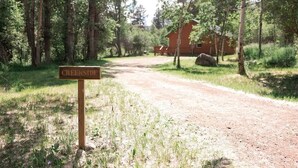 A dirt road leading to a wooden cabin labeled "Creekside" surrounded by trees. - Creekside Chalet, Private Creekside Chalet (Story)