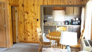 A cozy room with a wooden ceiling, a ceiling fan, a sofa with patterned cushions, a dining table with chairs, and a kitchen area in the background. - Creekside Chalet, Private Creekside Chalet (Story)