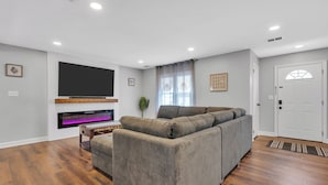Una sala de estar moderna con un sofá modular, un televisor de pantalla plana montado en la pared y piso de madera.