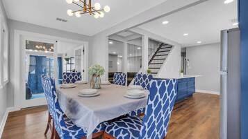 A modern dining area with a round table, blue patterned chairs, and a chandelier.