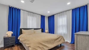 Un dormitorio con cama, mesitas de noche y cómoda.