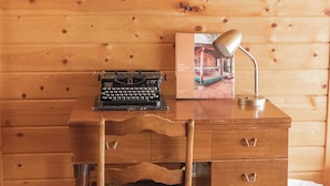 Un bureau en bois, sur lequel se trouvent une machine à écrire, une lampe et un livre intitulé « The Wagon Box ».