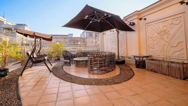 A patio area with a circular seating arrangement, a swing chair, and a large umbrella. - Shankee Chain Hotel (Xinyi Zhongxing Avenue) (Xinyi)