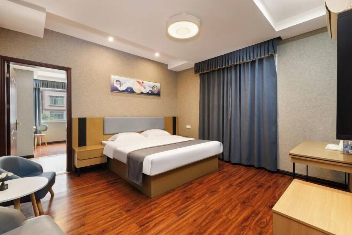 A hotel room with a bed, bedside tables, a desk, and a chair.