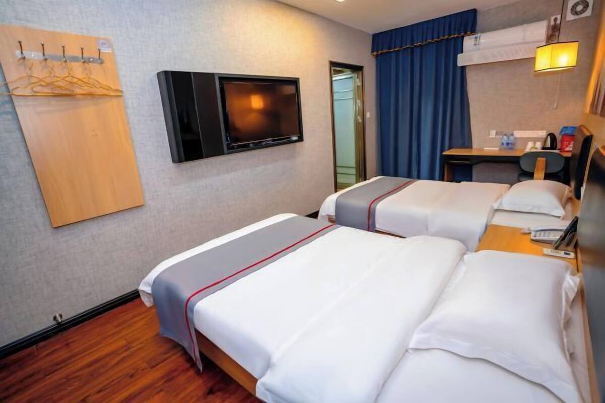 A hotel room with two beds, a TV, a desk, and a wardrobe.