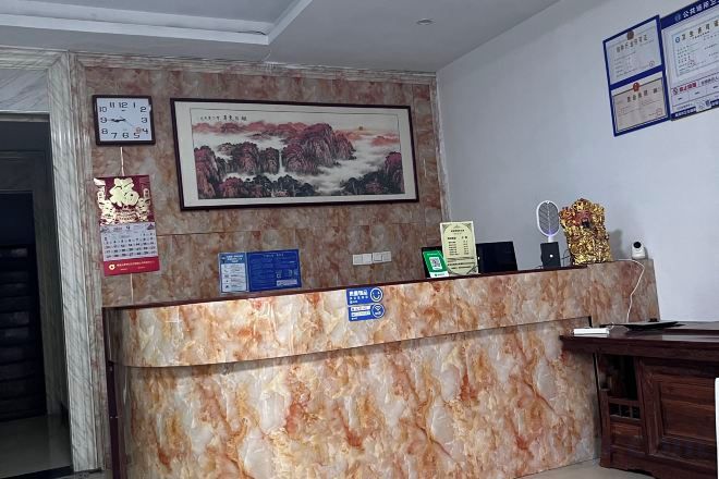 Una recepción con encimera de mármol, un cuadro enmarcado encima y un calendario en la pared.