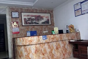 Una recepción con encimera de mármol, un cuadro enmarcado encima y un calendario en la pared.