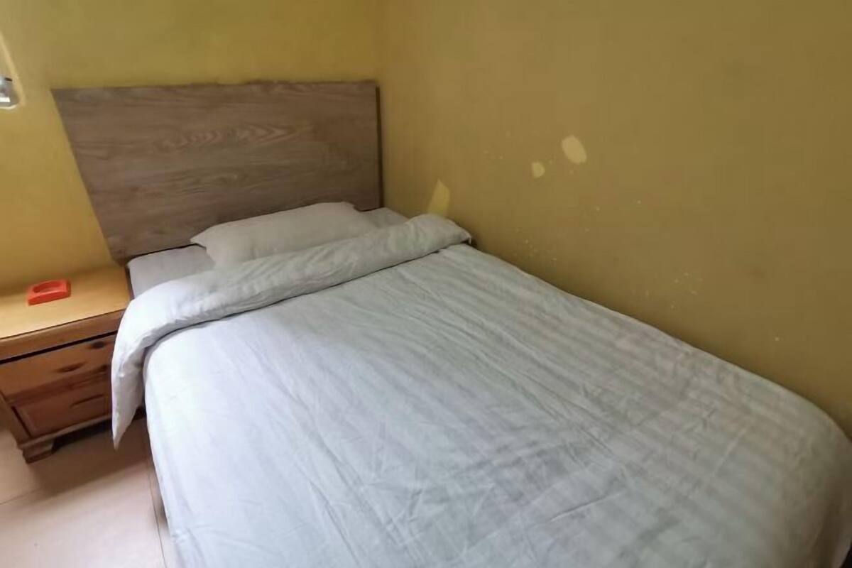 Ein Einzelbett mit hölzernem Kopfteil in einem Zimmer mit gelben Wänden.