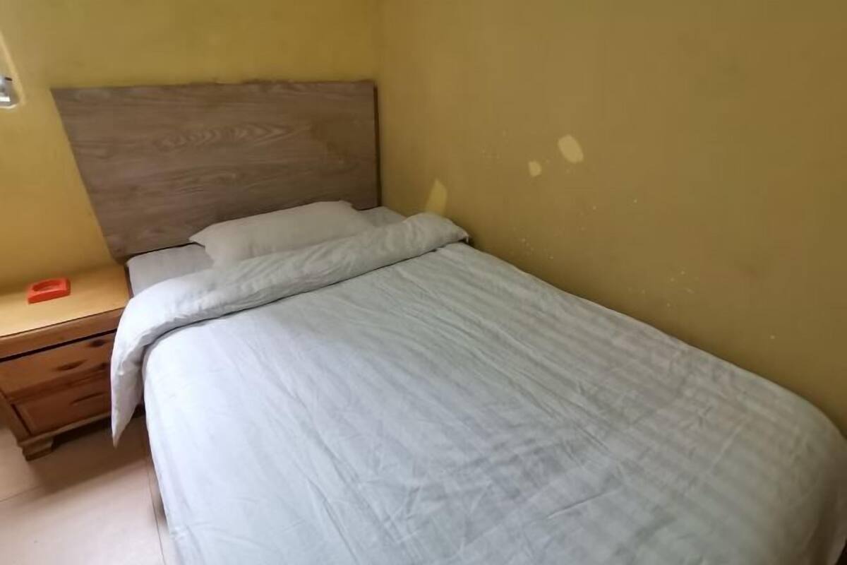 Ein Einzelbett mit Holz Kopfteil in einem Zimmer mit gelben Wänden.
