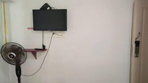 Un téléviseur fixé au mur, une prise de courant et un ventilateur.